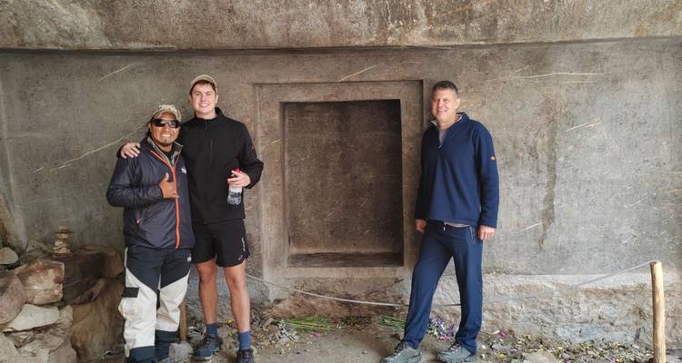Trois randonneurs posant dans une alcôve de pierre aux ruines incas.