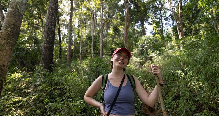 Smiling hiker wearing red cap standing on lush forest trail