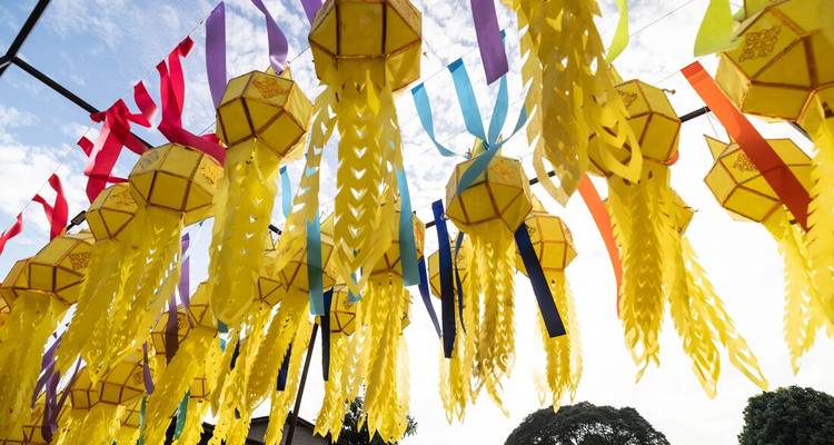 Bright yellow paper lanterns and colourful ribbons hanging overhead against sky