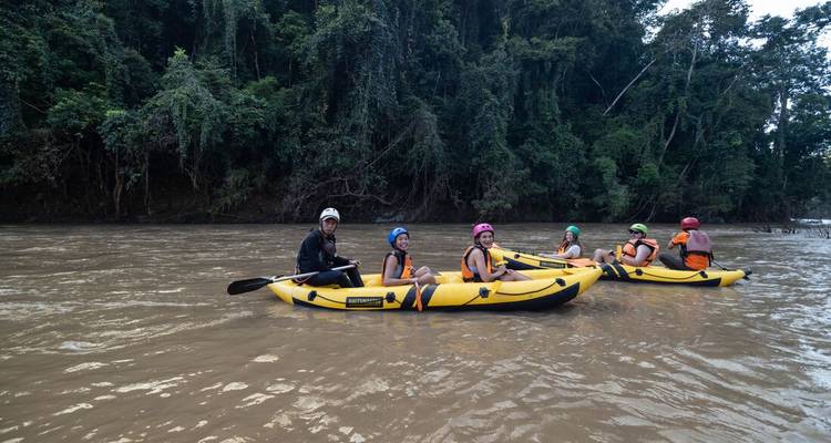 Adventurers in yellow inflatable kayaks floating on muddy jungle river