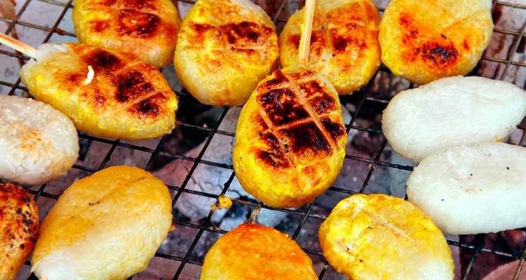 Grilled sticky rice cakes browning on metal grate over charcoal