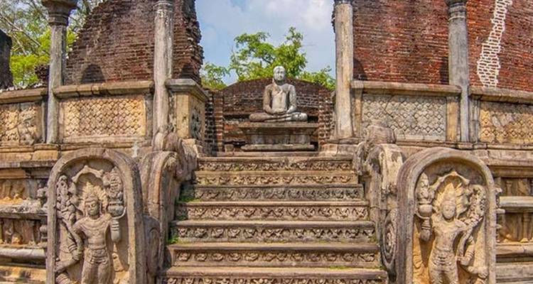 Steintreppe, flankiert von kunstvollen Schnitzereien, führt zu sitzendem Buddha inmitten antiker Tempelruinen.