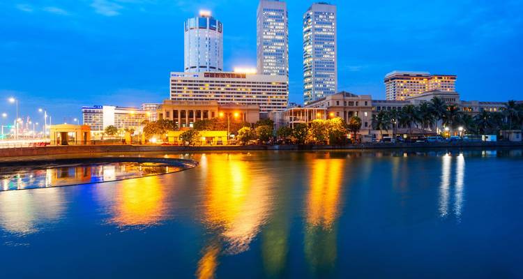 Nachtansicht der Skyline von Colombo mit lebendigen Lichtern, die sich im ruhigen Seewasser spiegeln.