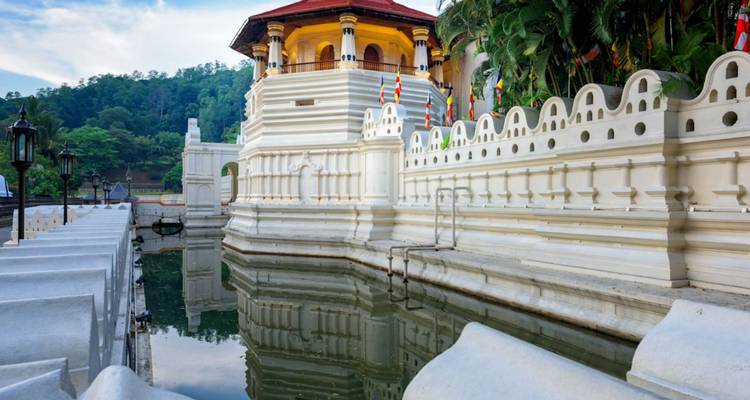 Seitenansicht des Zahntempels, der sich im umgebenden Wassergraben unter weichem Abendlicht spiegelt.