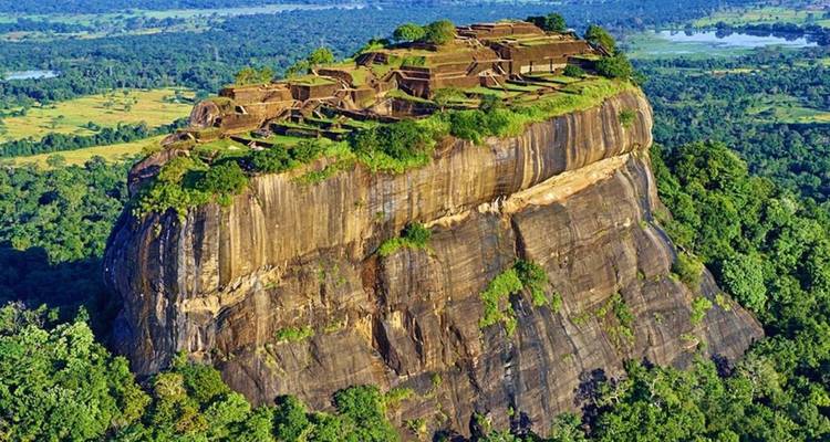 Luftaufnahme von archäologischen Ruinen auf dem flachen Gipfel des Sigiriya-Felsens, umgeben von dichtem Dschungel.