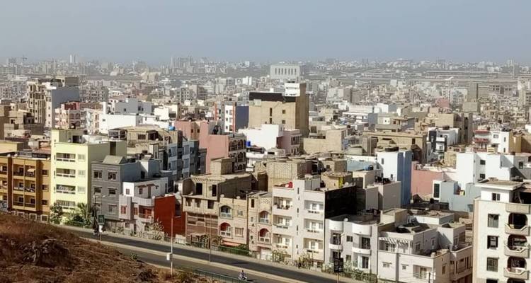 Uitgestrekt stedelijk silhouet van lage gebouwen die zich uitstrekken naar een wazige horizon onder een bleke hemel
