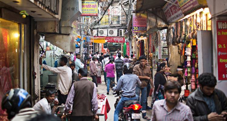 Une ruelle de marché étroite et animée dans le Vieux Delhi est remplie d'acheteurs, de vendeurs et d'enseignes de magasins colorées.
