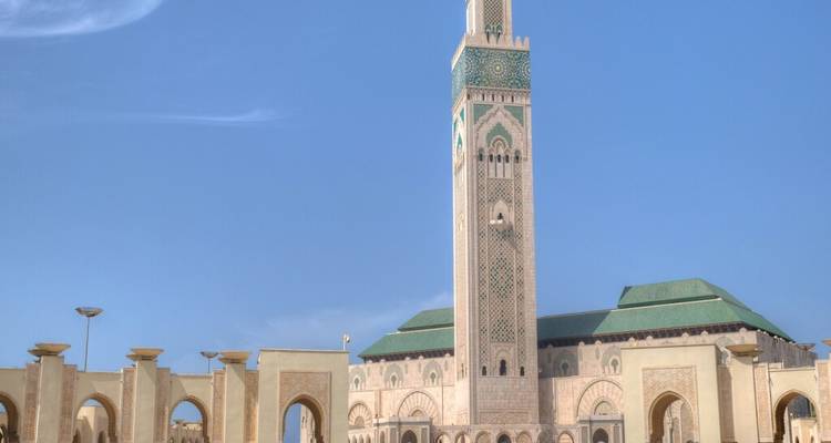 Mosquée Hassan II de grande taille avec un minaret orné s'élevant sur un ciel bleu dégagé à Casablanca