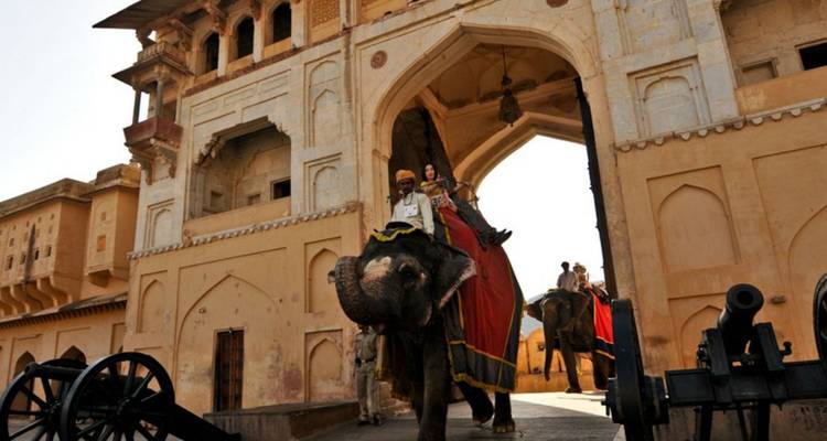Toeristen rijden op een versierde olifant door een boogvormige poort bij Amber Fort.