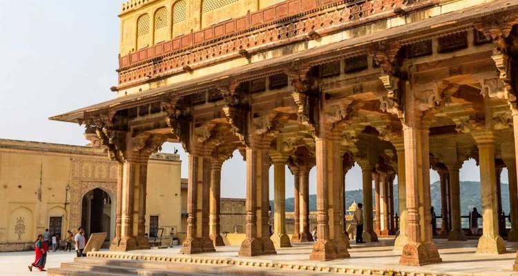 Bezoekers wandelen door sierlijke zuilengang bij Amber Fort met gebeeldhouwde zandstenen zuilen.