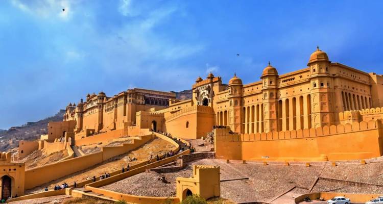 Breed panorama van Amber Fort's lange gevel en helling die de heuvel oploopt tegen blauwe hemel.