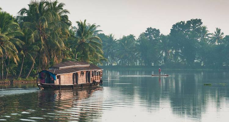 Een traditionele houten woonboot vaart door de mistige binnenwateren terwijl een eenzame visser in de buurt peddelt.