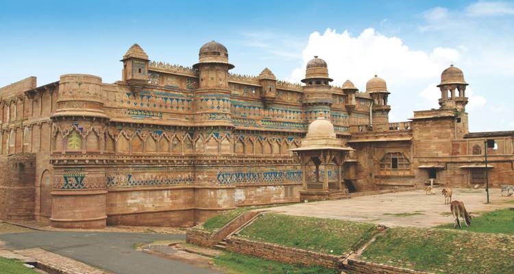 Massive sandstone walls and blue-tiled details of Gwalior Fort under a bright sky.