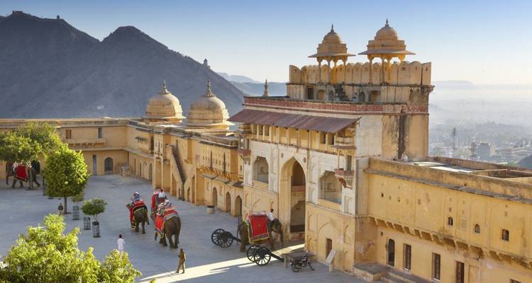 Olifanten die bezoekers dragen beklimmen de helling naar de sierlijke toegangsplaats van Amer Fort bij zonsopgang.