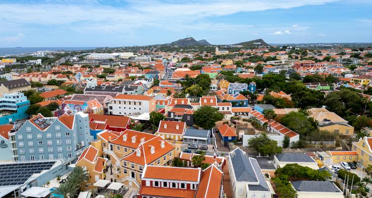 Aerial panorama of a Caribbean town with a sea of orange-roofed colonial houses stretching toward hilly terrain