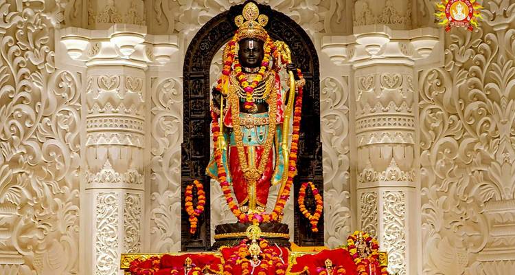 Sierlijk versierde zwarte stenen godenbeeldbeeld omhangen met bloemen in een rijkelijk gebeeldhouwde witte marmeren schrijn