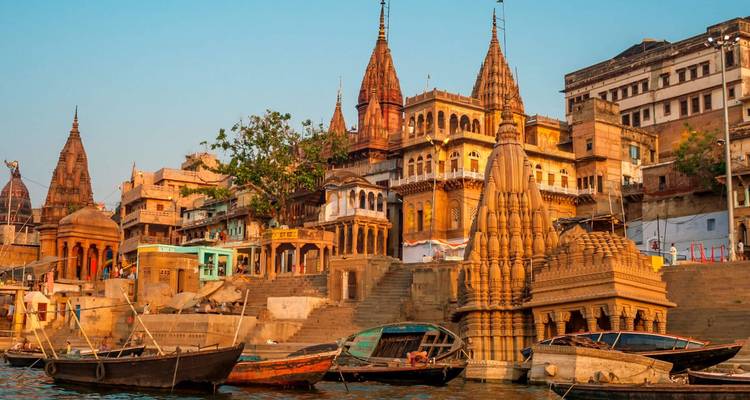 Kleurrijke tempels en ghats van Varanasi langs de Ganges rivier tijdens het gouden uur met houten boten op de voorgrond