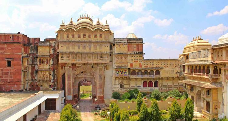 Großes Tor und Palastfassade reich verziert mit Rajput-Fresken vor einem strahlend blauen Himmel
