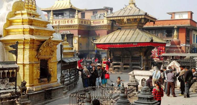 Pelgrims en bezoekers verzamelen zich tussen gouden heiligdommen en gebedsmolens in het Swayambhunath-complex