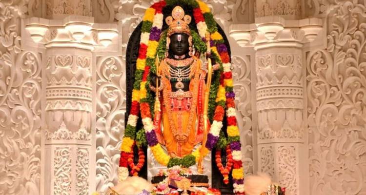 Garland-adorned black stone deity enshrined in an ornately carved white marble altar