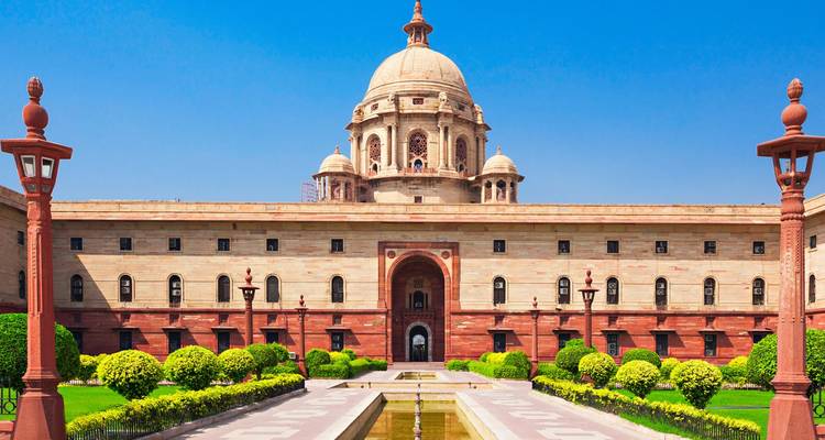 Grand domed sandstone government building with symmetrical gardens and reflecting pool