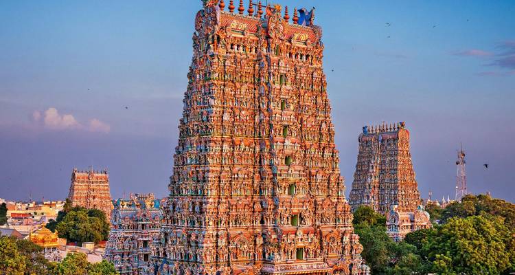 Les gopurams imposants et richement décorés du temple de Meenakshi Amman rayonnent dans la douce lumière du soir au-dessus du paysage urbain.