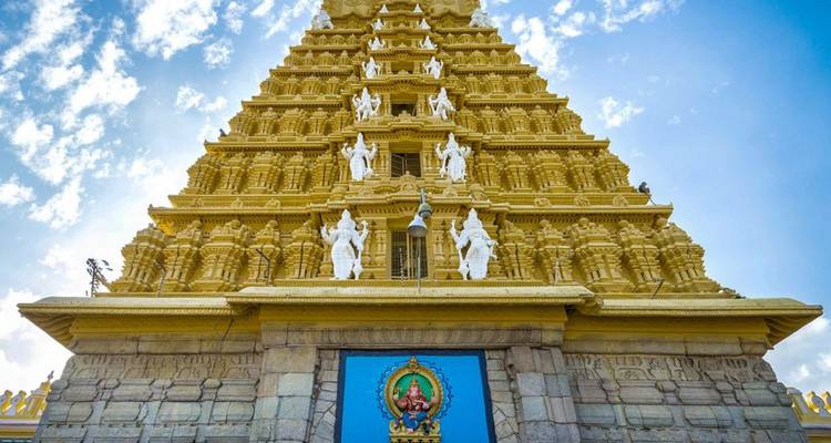 Goldener Gopuram-Turm des Chamundeshwari-Tempels, reich verziert mit Schutzgottheiten vor blauem Himmel.