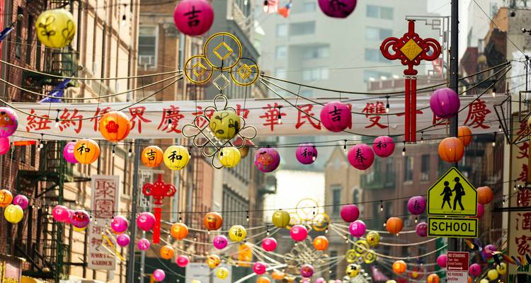 Des lanternes en papier colorées et des bannières festives suspendues au-dessus d'une rue animée de Chinatown.