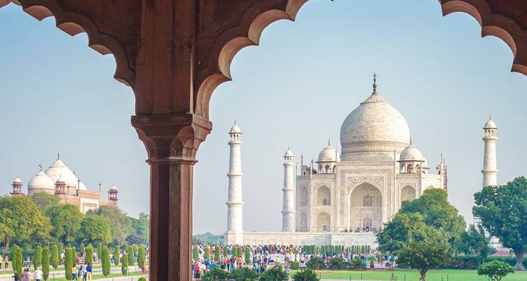 De Taj Mahal omlijst door een Mogol-boog met verzorgde tuinen en bezoekers op de voorgrond.