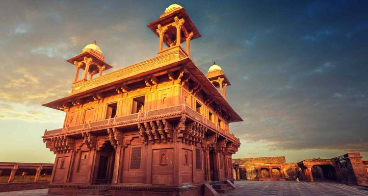 Zonsondergangslicht baadt het rode zandstenen paviljoen van Fatehpur Sikri in een dramatische lucht