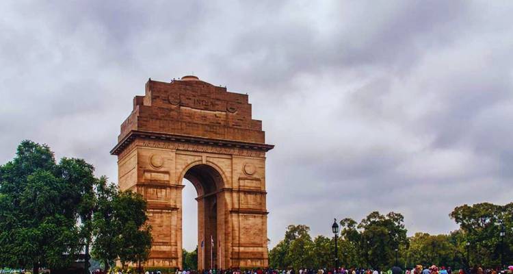 India Gate rijst op onder dreigende grijze wolken met menigten verzameld aan de voet