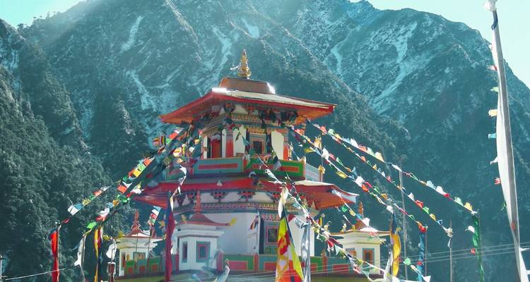 Bunte Gebetsfahnen, die um eine lebendige buddhistische Stupa flattern, vor schneebestäubten Gipfeln