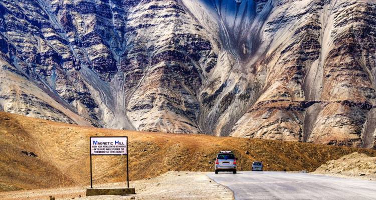 Malerische Bergstraße am Magnetic Hill mit markanten gestreiften Klippen, die sich darüber erheben