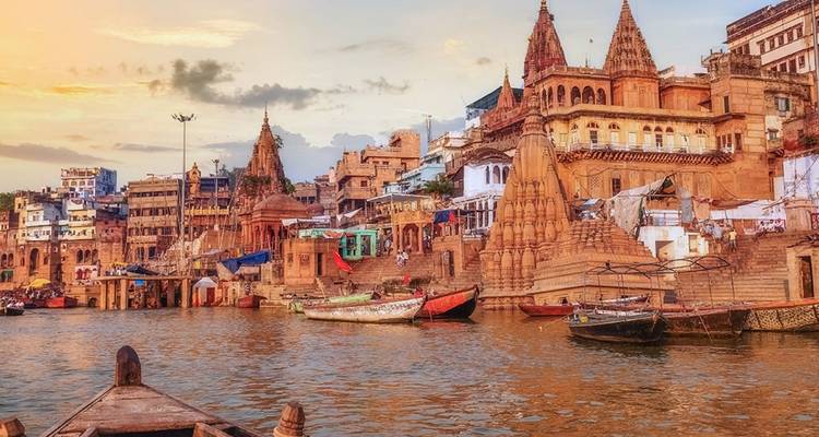 Colourful ghats and temples lining the Ganges River in Varanasi at sunset.