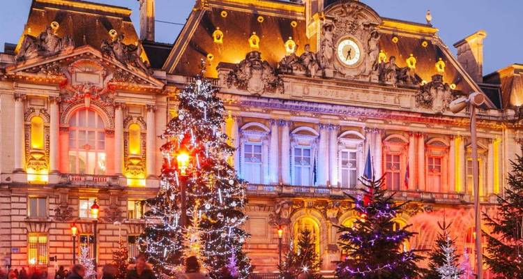 Mairie élégante d'une ville française illuminée de guirlandes de Noël multicolores et d'arbres décorés au crépuscule.