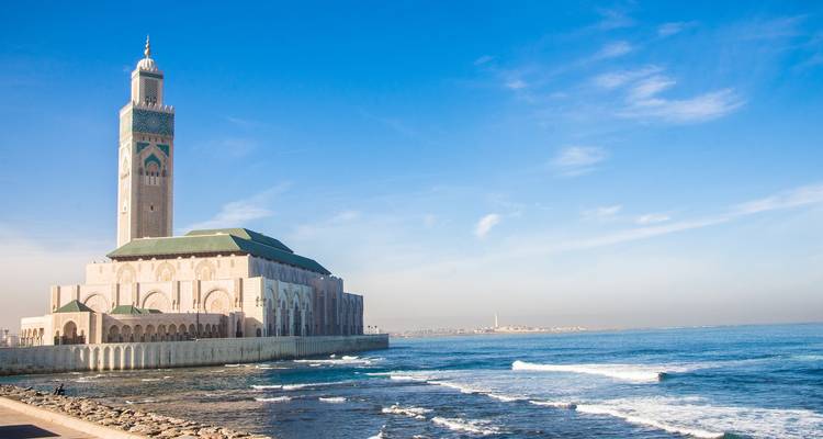 Hassan II Mosque extending into Atlantic Ocean on bright clear morning.