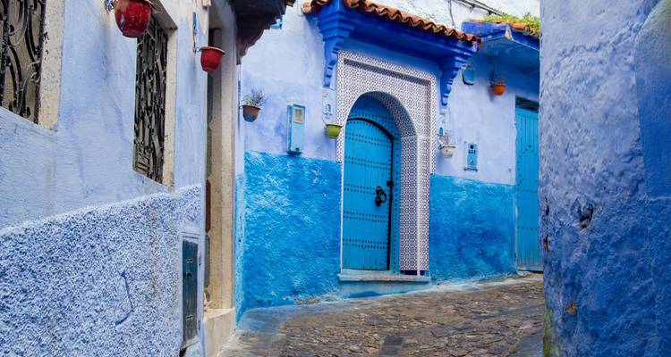 Colorful blue alley with arched doorway in Chefchaouen’s medina.