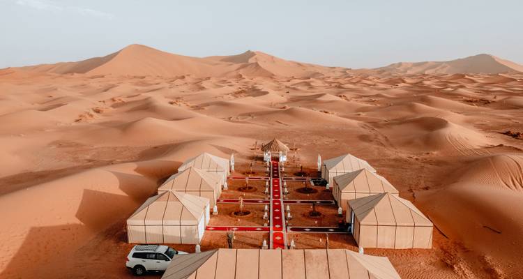 Aerial view of orderly luxury desert camp surrounded by endless sand seas.