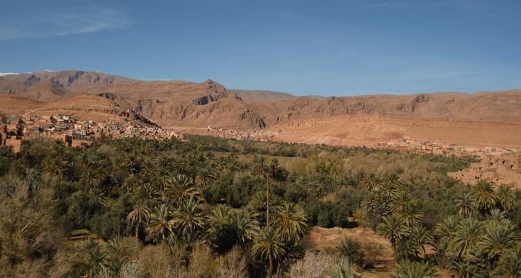 Verdant oasis of palm groves nestled between desert mountains and adobe villages.