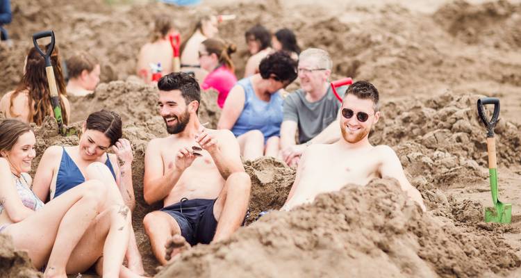 Strandgangers ontspannen in handgegraven warme baden op een zandige kust.