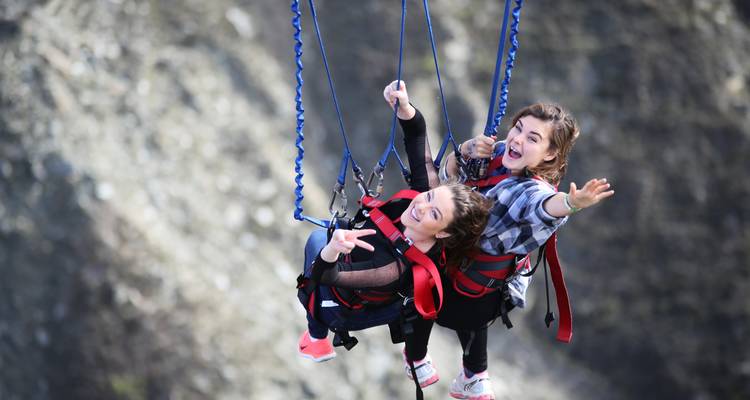 Twee sensatiezoekers zwaaien hoog boven een canyon op een tandem bungeejump.