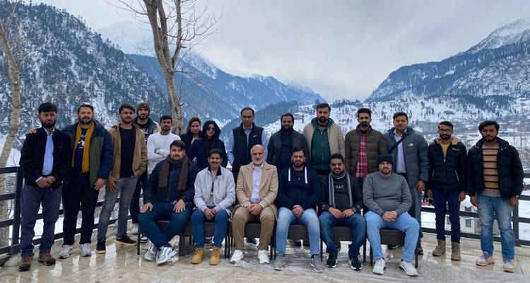 Grupo grande de viajeros posando en una terraza nevada con un profundo valle montañoso detrás