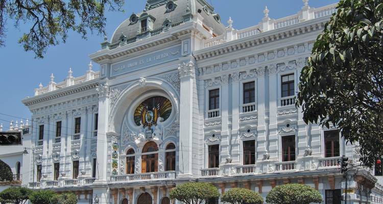 Grand white neoclassical Supreme Court building with manicured topiary trees in front.