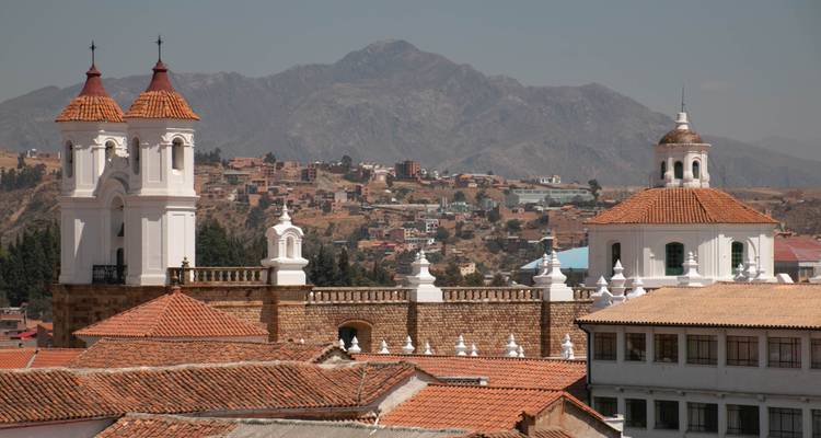 Rooftop view of colonial bell towers and terracotta tiles with mountainous backdrop in Sucre.