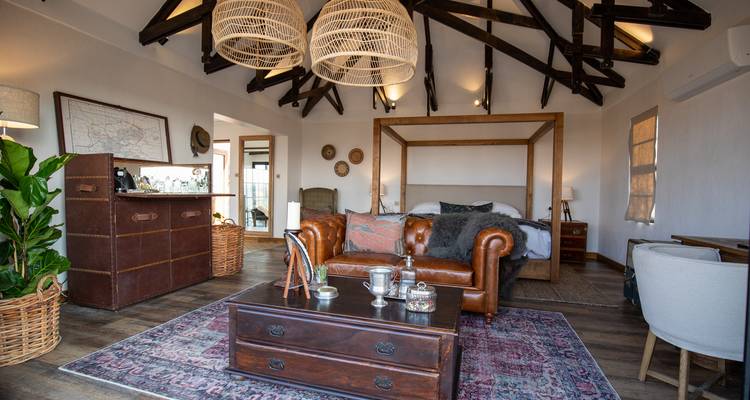 Stylish rustic lodge suite with exposed beams, leather sofa, four-poster bed and eclectic decor