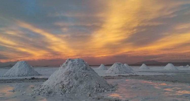 Small salt mounds dot the Uyuni flats at sunrise with warm clouds painted across the sky.