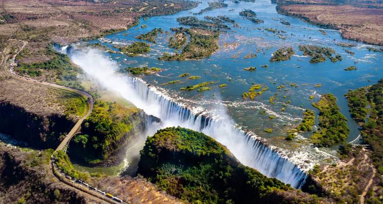 Aerial view of Victoria Falls spanning the Zambezi River with spray and islands visible from above.