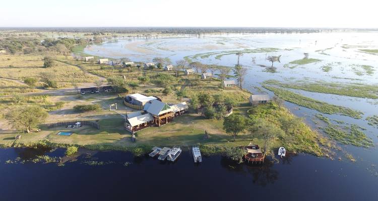 Aerial view of a lodge complex on an island amid vast seasonal floodplains and winding water channels.