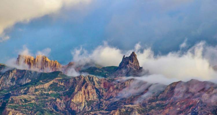 Dramatic multicoloured Andean peaks shrouded in drifting clouds and mist
