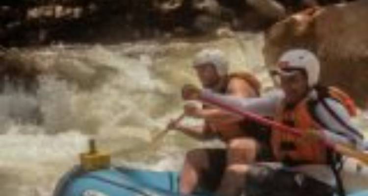 Blurry action shot of two rafters paddling through white-water rapids.